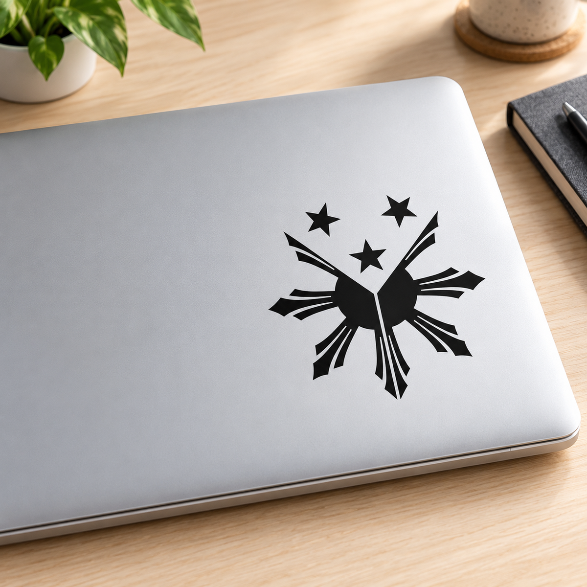 Black Filipino sun and three stars transfer decal mockup on silver laptop